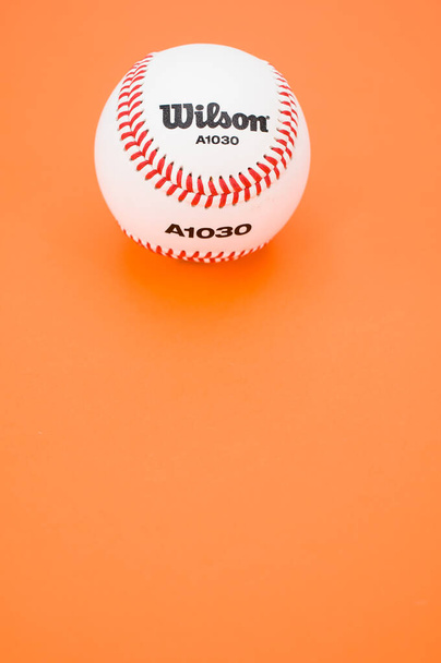 INVERIGO, ITALY - Dec 08, 2021: isolated baseball ball on orange paper background with text space - Foto, imagen