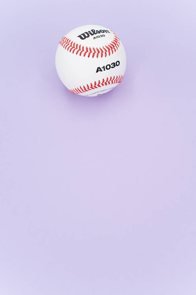INVERIGO, ITALY - Dec 08, 2021: isolated baseball ball on a lilac background with text space - Φωτογραφία, εικόνα