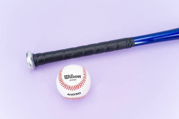INVERIGO, ITALY - Dec 08, 2021: isolated baseball ball and bat on a lilac background with text space - Fotografie, Obrázek