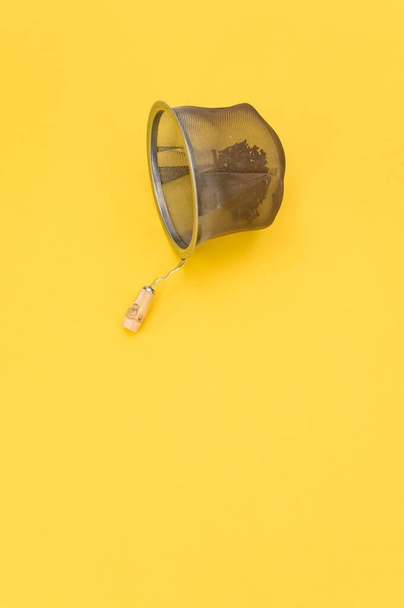 metal tea strainer on a yellow tabletop background with text space - Fotó, kép