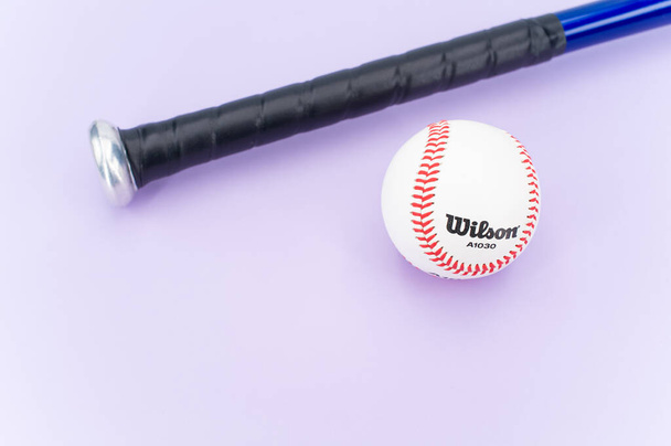 INVERIGO, ITALY - Dec 08, 2021: isolated baseball ball and bat on a lilac background with text space - Zdjęcie, obraz