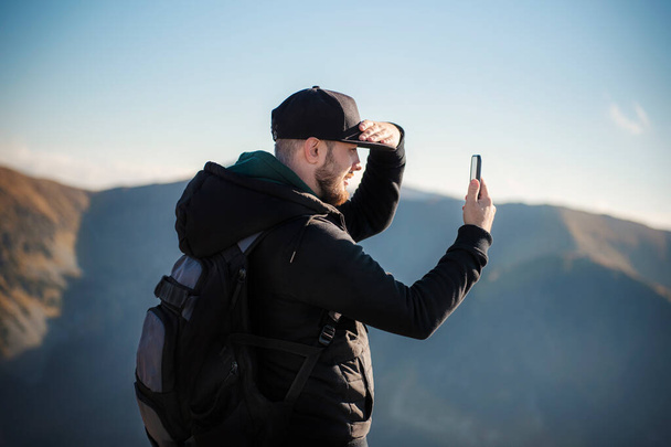Yakışıklı genç adam akıllı telefon dağ manzarasıyla kapışıyor. Kasprowy Wierch. Polonya. - Fotoğraf, Görsel