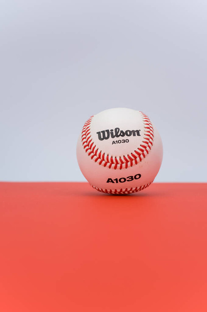 INVERIGO, ITALY - Dec 08, 2021: isolated baseball ball on a red background with text space - 写真・画像