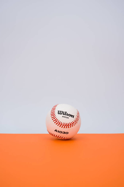 INVERIGO, ITALY - Dec 08, 2021: isolated baseball ball on orange paper background with text space - Foto, afbeelding
