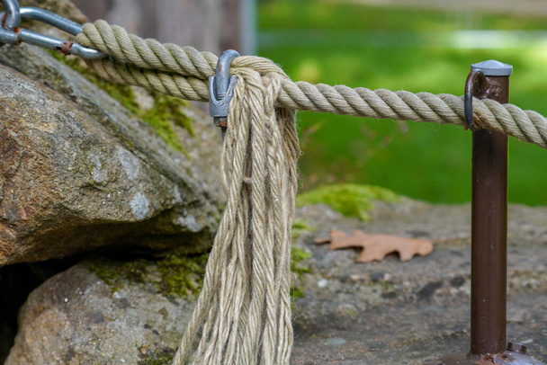 A closeup of a rope tied to fences in a park oputdoors - Photo, Image
