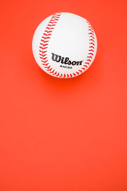 INVERIGO, ITALY - Dec 08, 2021: isolated baseball ball on a red background with text space - Fotó, kép