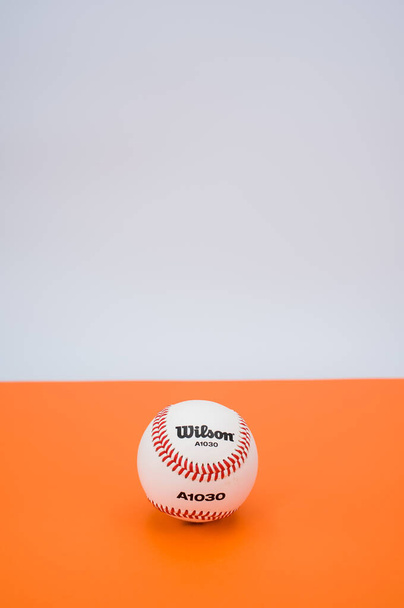 INVERIGO, ITALY - Dec 08, 2021: isolated baseball ball on orange paper background with text space - Foto, Imagen