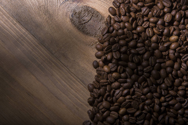 A top-view of fresh roasted coffee beans on a wooden table with copy space - Foto, imagen