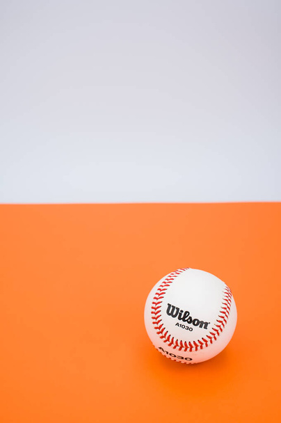 INVERIGO, ITALY - Dec 08, 2021: isolated baseball ball on orange paper background with text space - Фото, изображение