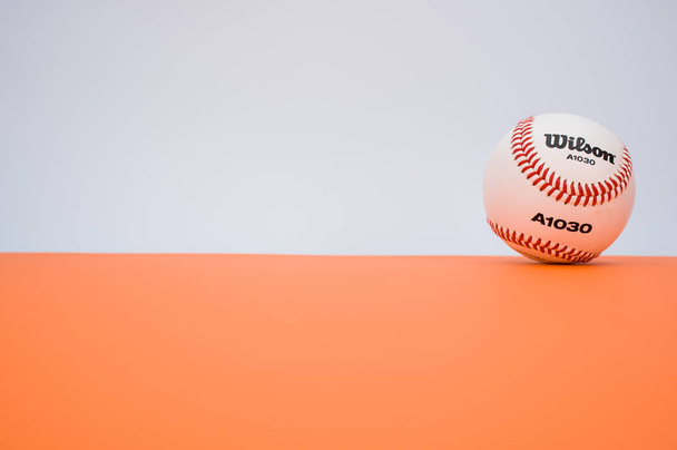 INVERIGO, ITALY - Dec 08, 2021: isolated baseball ball on orange paper background with text space - Valokuva, kuva