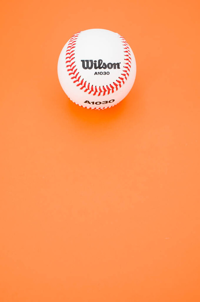 INVERIGO, ITALY - Dec 08, 2021: isolated baseball ball on orange paper background with text space - Zdjęcie, obraz