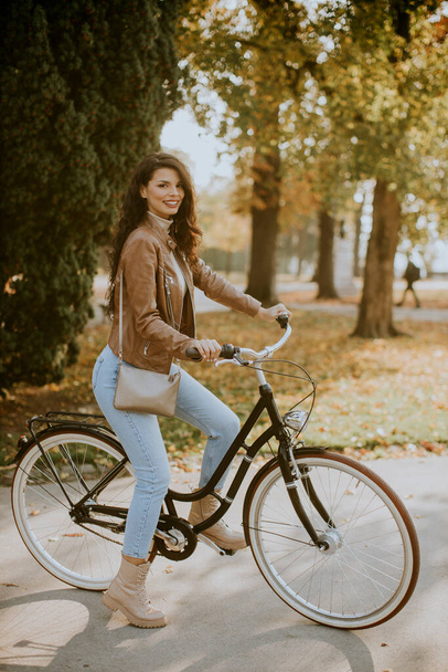 Güz gününde bisiklete binen güzel genç bir kadın. - Fotoğraf, Görsel
