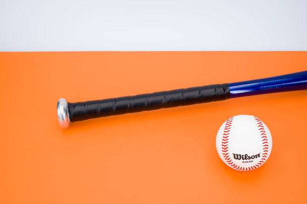 INVERIGO, ITALY - Dec 08, 2021: isolated baseball ball and bat on an orange background with text space - Foto, Bild