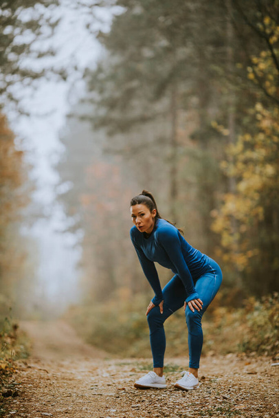 Pretty young woman take a break during outdoor exercise on the forest trail at autumn - Φωτογραφία, εικόνα