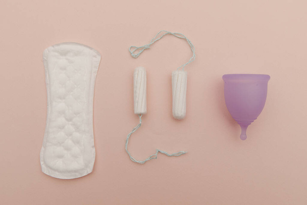 Pad, menstrual cup, tampon on a pink background. Concept of critical days and hygiene. Top view - 写真・画像