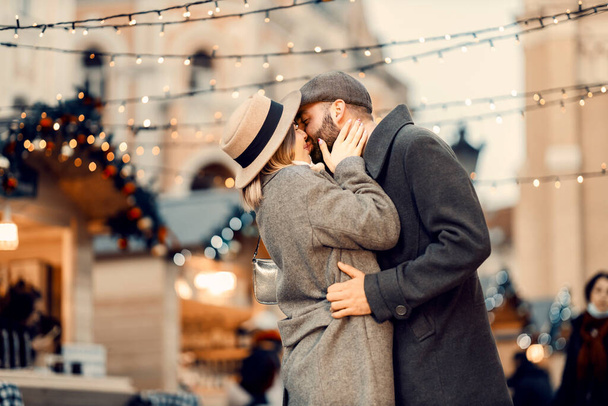 Weihnachtspaar küsst sich auf der Straße. Junges Liebespaar küsst sich an Weihnachten auf der Straße zärtlich. - Foto, Bild