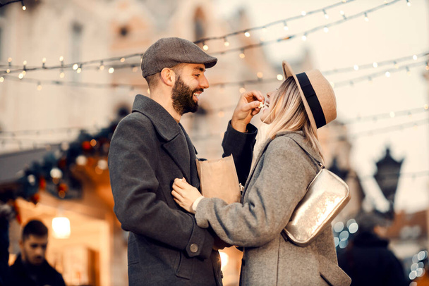 Christmas spouses feeding with popcorn outdoors on Christmas Day. A happy husband feeding his wife with popcorn while standing on the street on New Year's Day. - 写真・画像