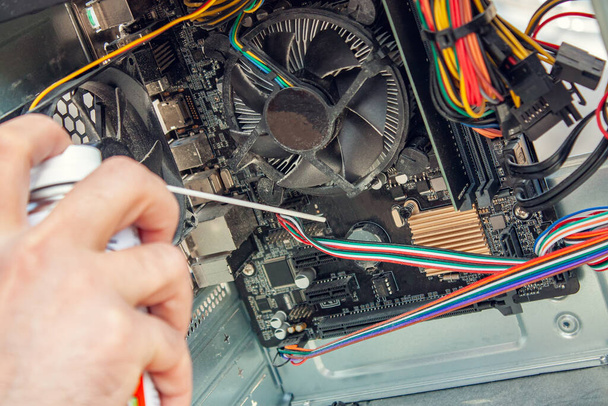 Maintenance and cleaning of the insides of the computer. Mans hand holds a cylinder of compressed air and cleans the insides of the computer - Photo, Image