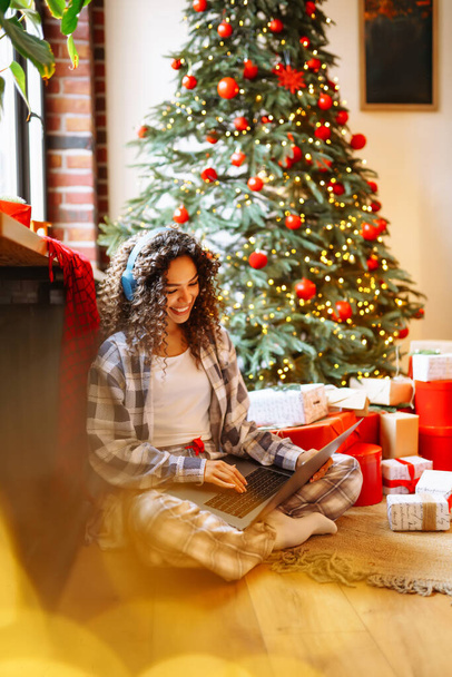 Christmas online holiday. Young woman uses laptop having video call with their family or friends.  New Years. Gift boxes.  - Foto, afbeelding