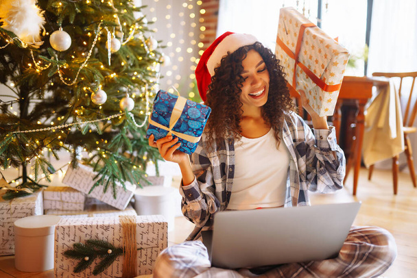 Christmas online holiday. Young woman uses laptop having video call with their family or friends.  New Years. Gift boxes.  - Photo, image