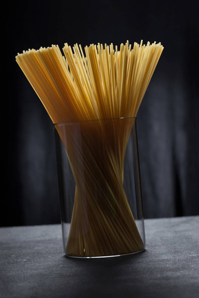 minimalistic image of spaghetti pasta in a glass jar close-up. - Photo, Image