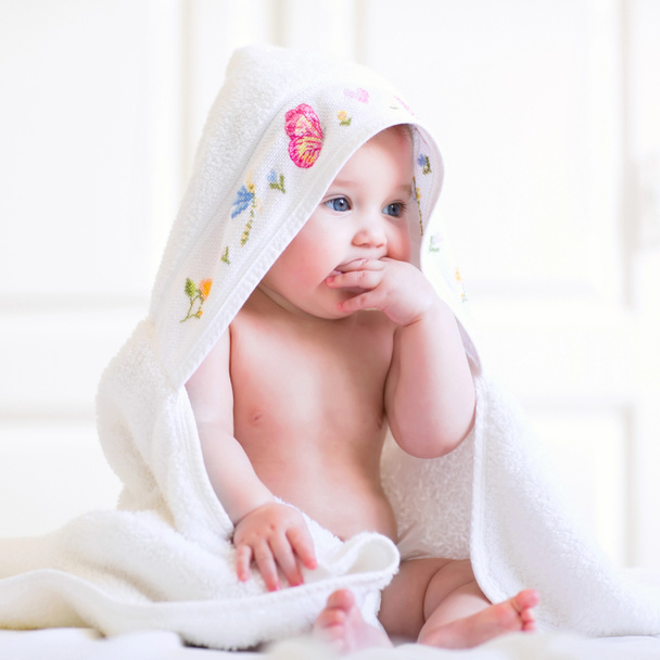 roztomilá holčička, sedící pod kapucí ručníku po koupeli - Fotografie, Obrázek