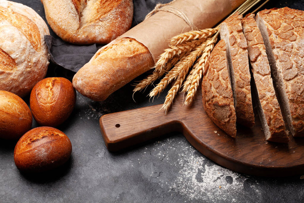 Различные виды хлеба на каменном столе - Фото, изображение