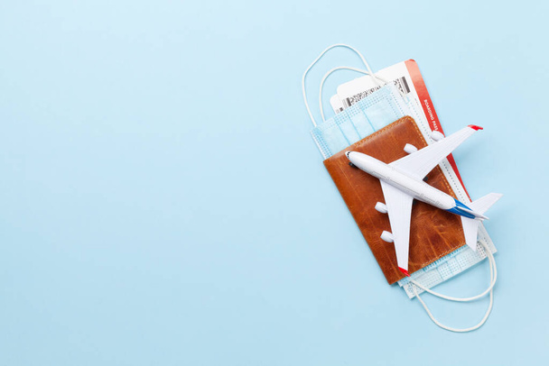 Travel and vacation concept. Trip accessories and items. Airplane toy over passport with airplane tickets and face masks. Top view flat lay with copy space - 写真・画像