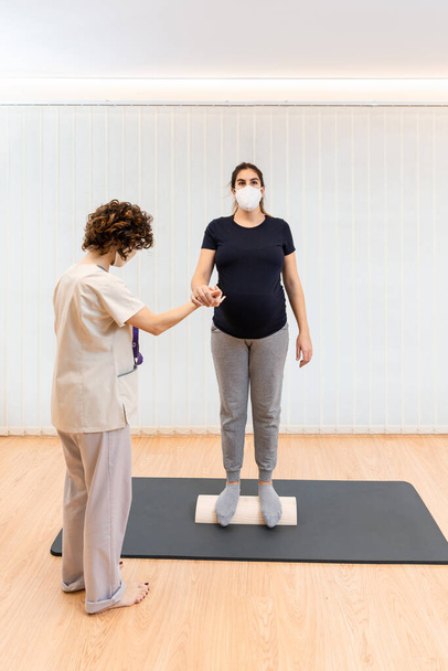 pregnant woman standing on a proprioceptive trunk for lumboabdominal and perineal walls with physiotherapist - Photo, Image
