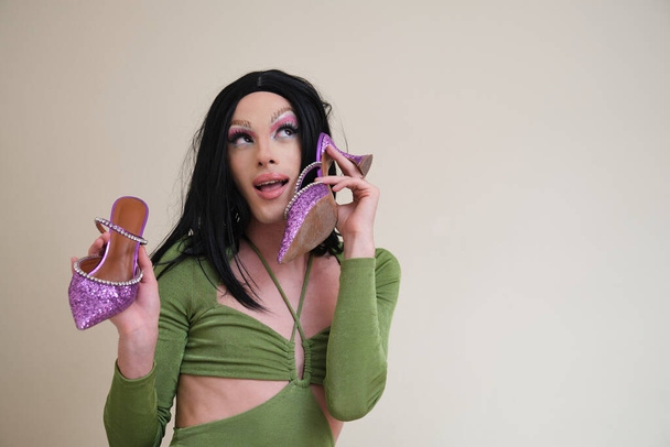 Portré egy drag queen személy pózol holding sarok bézs háttér. - Fotó, kép
