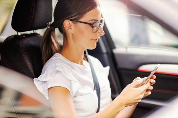 幸せな女性は彼女の車の中に座って、メッセージをテキストメッセージ。電話のある車の中の女性 - 写真・画像