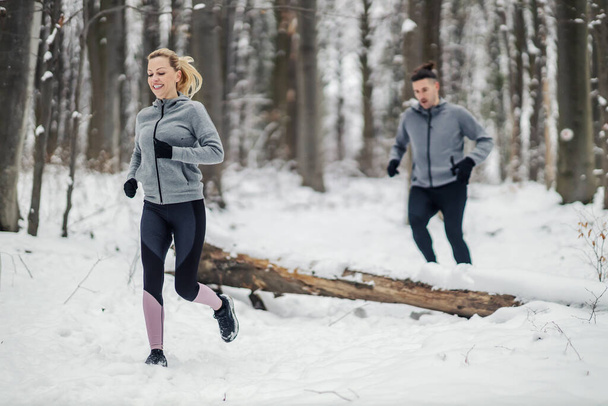 S'adapter couple course en forêt lors de la journée d'hiver enneigée. Relation, mode de vie sain, succès - Photo, image