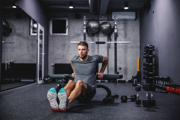 Sportovec dělá triceps kliky na sportovní lavičce v moderní tělocvičně. Koncept fitness tréninku, sportu, čerpacích svalů paží, press up - Fotografie, Obrázek