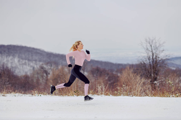 Karlı kış gününde doğada koşan hızlı sporcu kadın. Sağlıklı yaşam, sağlıklı alışkanlıklar, kış sporu. - Fotoğraf, Görsel