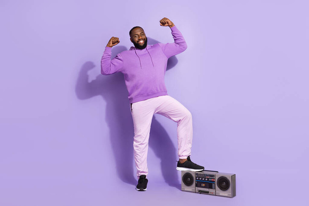 Full length body size view of attractive cheerful guy dj with tape player showing muscles isolated on violet purple color background - Фото, зображення