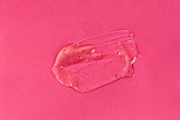 Liquid gel cosmetic product with shimmery particles and bubbles on pink background. Texture and background - Photo, image