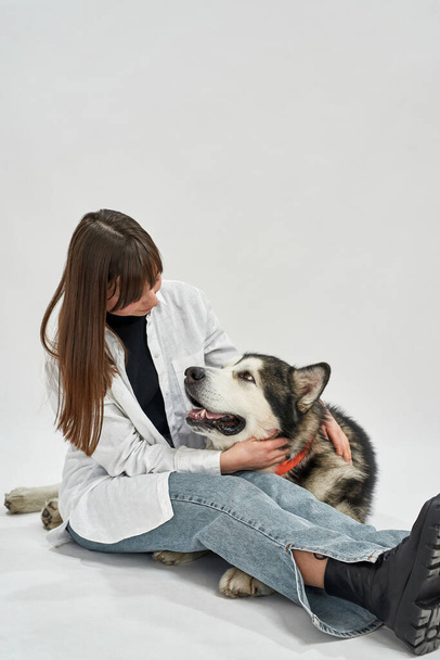 Girl embracing and looking on Siberian Husky dog - Фото, зображення