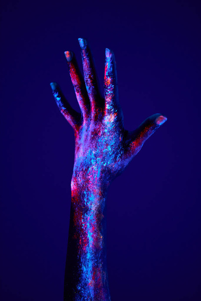 hand in neon light depicts the power or rising of human emotion, fluorescent art - Foto, afbeelding