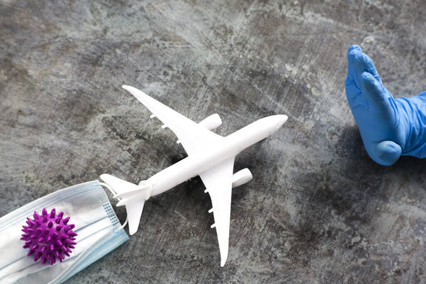 Una mano in un guanto blu mostra uno stop all'aereo che trasporta il coronavirus. Il divieto di viaggiare in aereo per la non proliferazione del coronavirus. Interrompi coronavirus - Foto, immagini