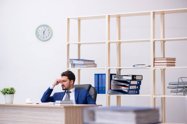 Giovane dipendente maschio e troppo lavoro in ufficio - Foto, immagini