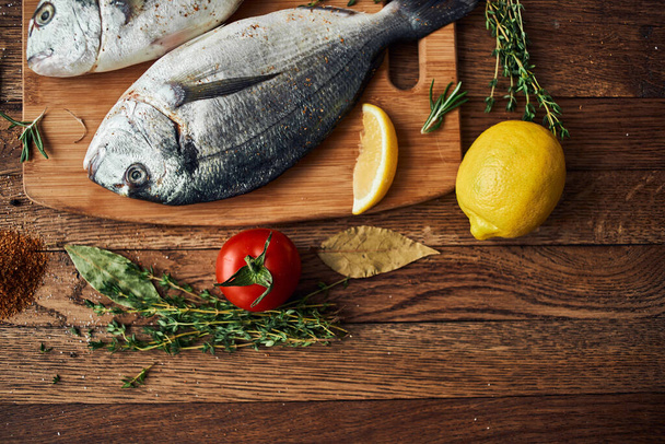 sea fish fresh ingredients lemon on wooden board - Foto, Bild