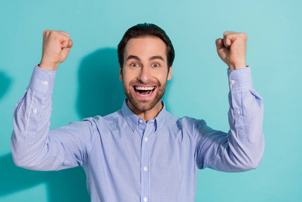 Photo of astonished guy raise fists rejoice lucky investment opportunity wear violet shirt isolated teal color background - Foto, imagen
