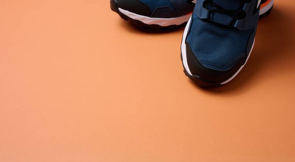 pair of blue textile sneakers on orange background, top view - Фото, зображення