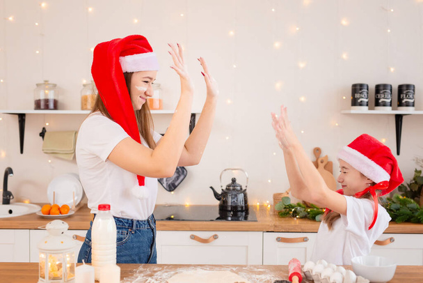 Children prepare Christmas cookies in a cozy kitchen. The sisters prepare a festive meal for the family together. Cute girls bake, play and fool around with flour. The concept of a child chef - Photo, image