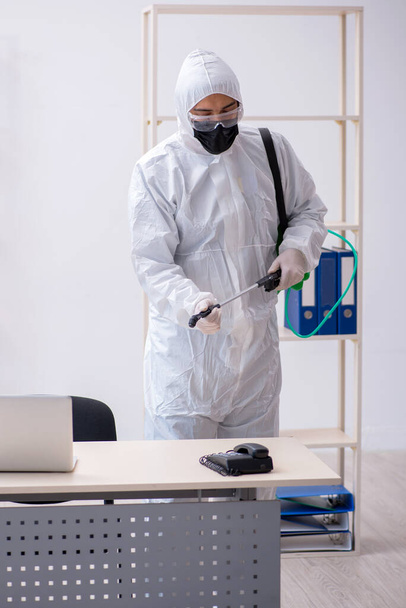 Молодой подрядчик дезинфицирует офис во время пандемии - Фото, изображение