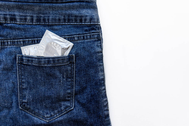 Due pacchetti di preservativi sono in una tasca di jeans. Focus selettivo.Concetto di educazione sessuale per gli adolescenti. Scelta della contraccezione da parte dei partner. Pianificare i bambini in famiglia. Prendersi cura della salute del partner sessuale. - Foto, immagini