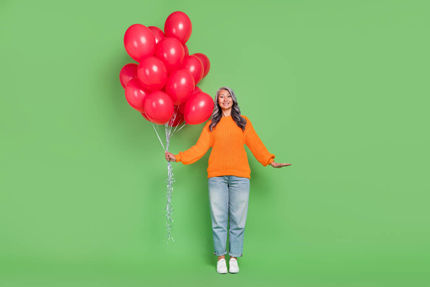 Full length photo of sweet grey hair old lady with balloons wear jumper jeans shoes isolated on green background - Foto, Imagem