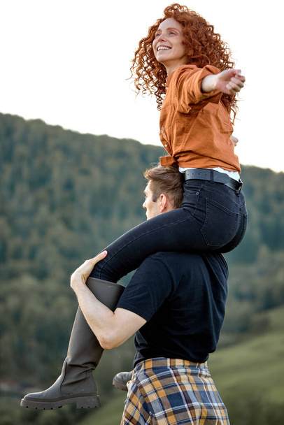 Happy redhead woman and guy trekking in mountains at summer. Positive couple hiking - 写真・画像
