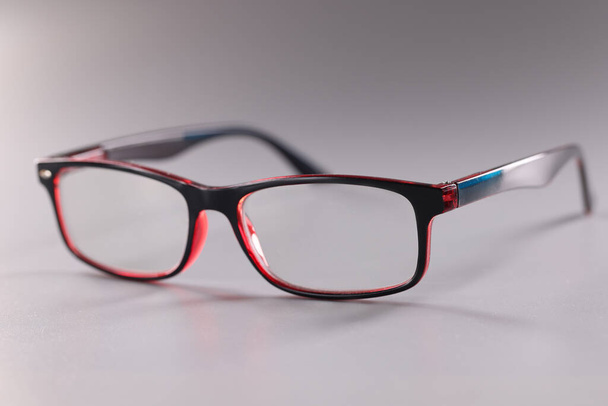 Fashionable plastic glasses red-black on gray background - Photo, Image