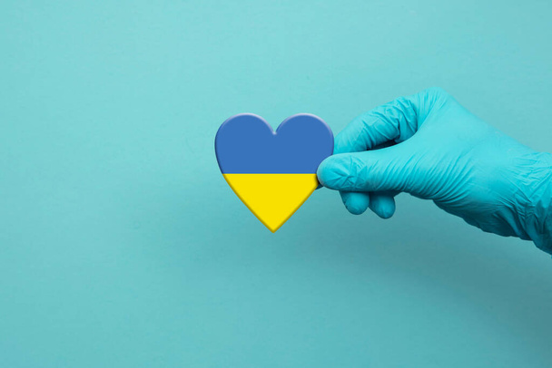Medical workers hand wearing surgical glove holding Ukraine flag heart - Foto, Imagem